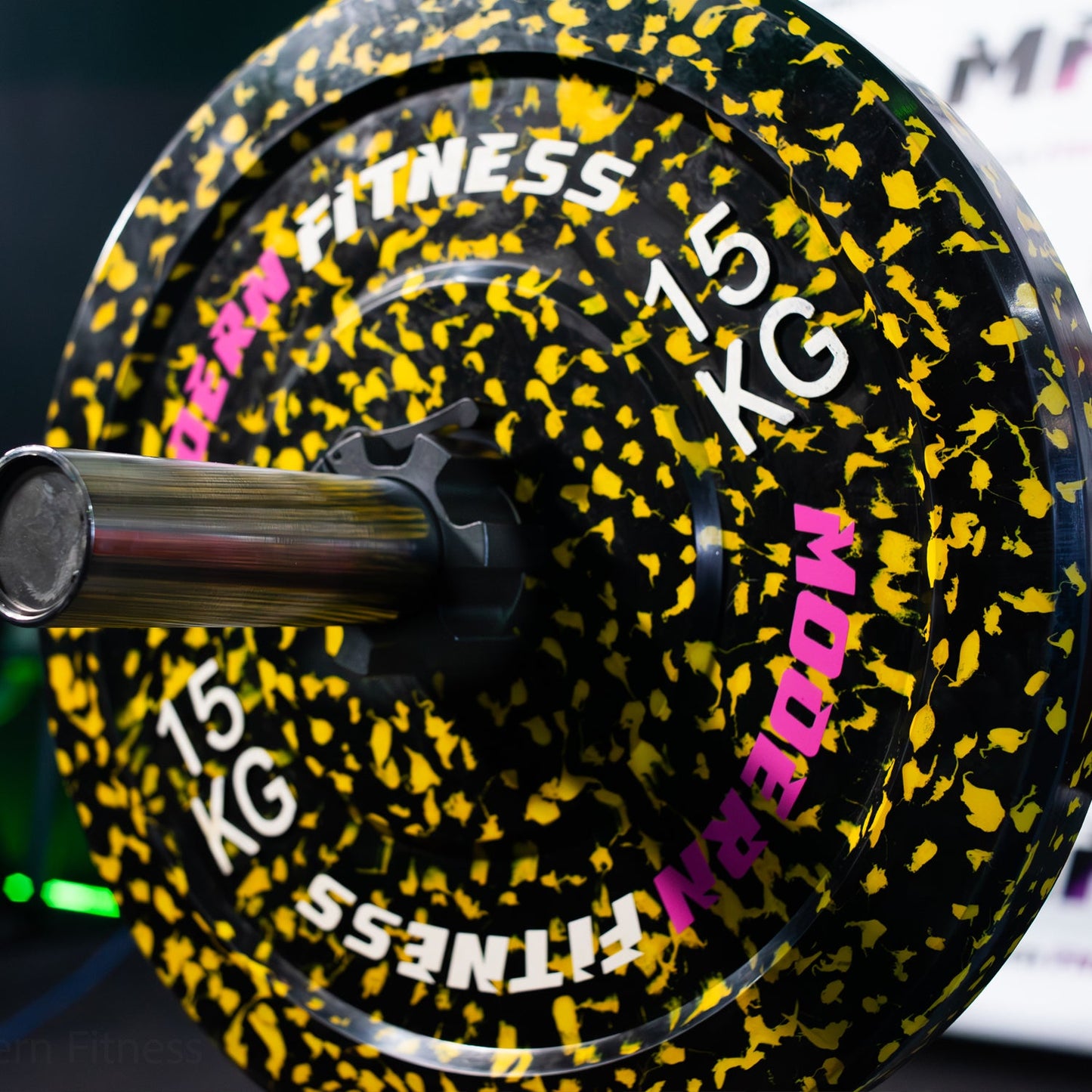 modernfitness 15kg camouflage rubber olympic weight plate with yellow and black speckled design on a barbell