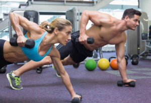 Image of two people performing the same fitness workout in a commercial gym, using modern and high quality fitness equipment