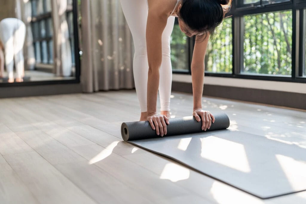 Image of a single person rolling a gym matt after finishing a fitness workout. 